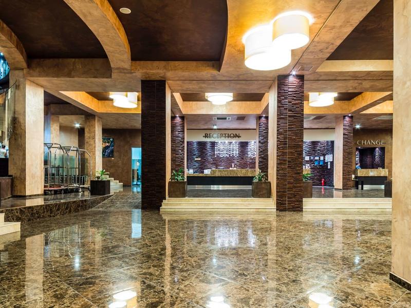 Große Hotellobby mit poliertem Marmorboden, Säulen und moderner Beleuchtung.