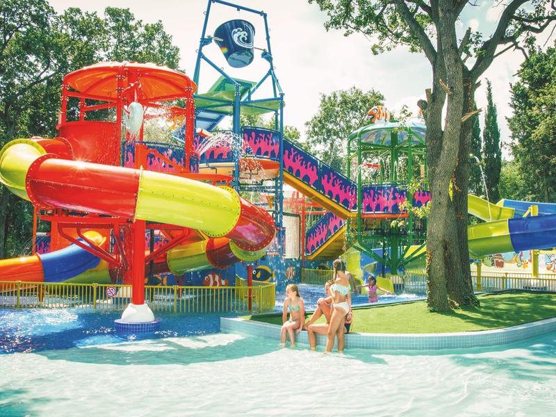 Bunter Wasserspielplatz mit Rutschen und Wasserbecken in einem Ferienpark.