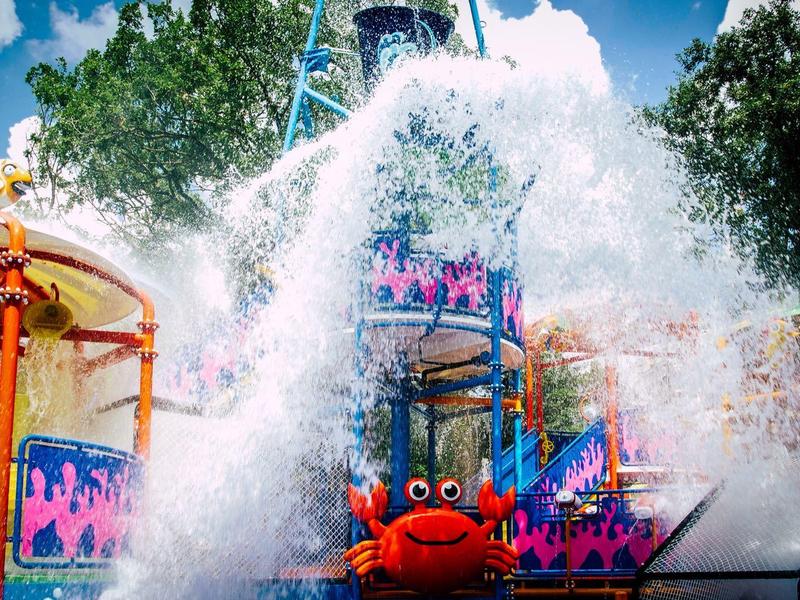 Wasserattraktion im Freizeitpark mit spritzendem Wasser und bunten Figuren.