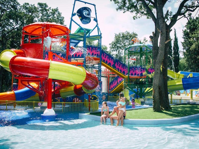 Bunter Wasserrutschenpark mit mehreren Rutschen und Menschen im Wasserbereich.