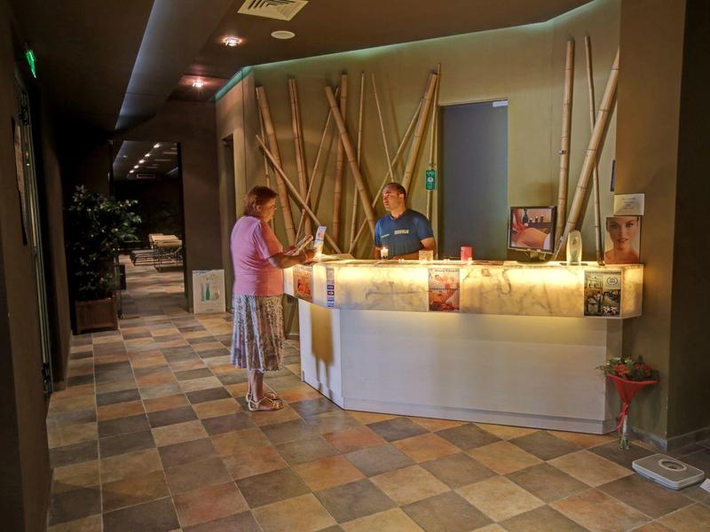 Empfangsbereich eines Hotels mit Rezeption und Gästen in warm beleuchtetem Raum.