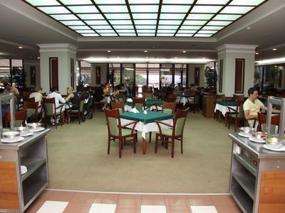 Großes, helles Restaurant mit vielen Holztischen, Stühlen und Buffetwagen an den Seiten.