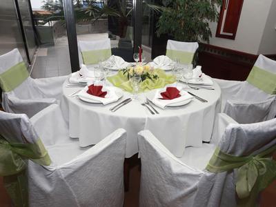 Runder Tisch mit weißem Tischtuch, acht Stühlen mit weißen Hussen und grünen Schleifen, gedeckt.