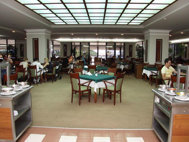 Großes, helles Restaurant mit vielen Holztischen, Stühlen und Buffetwagen an den Seiten.