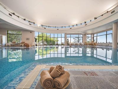 Indoor swimming pool with large windows and rolled towels in the foreground