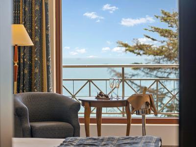 Cozy seating area with table and chair on balcony overlooking the sea.