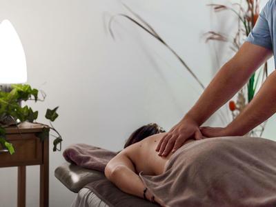 Person receiving a back massage in a calm room with a plant beside the massage table.