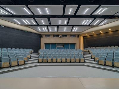 Modern auditorium with blue seating rows and bright ceiling lights.