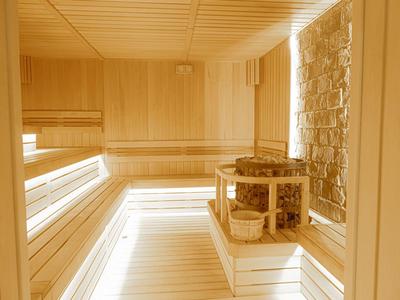 Sauna lumineuse avec boiseries et poêle en pierre dans le coin.