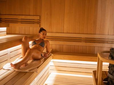Femme se détendant dans un intérieur de sauna en bois moderne et bien éclairé.