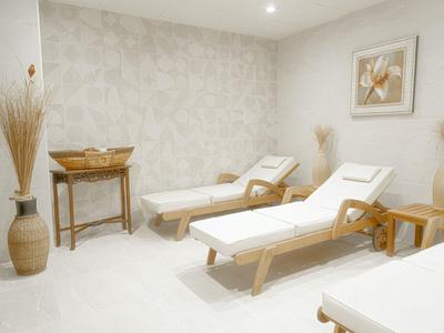 Salle de détente lumineuse avec deux transats, des vases et une petite table contre le mur.