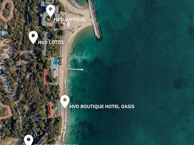 Vue aérienne d'une côte avec des hôtels et des plages le long d'une mer bleue.