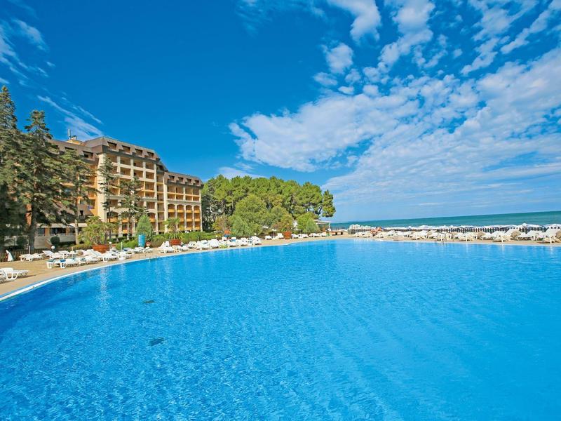 Large pool in front of a hotel with blue water surface and clear sky.
