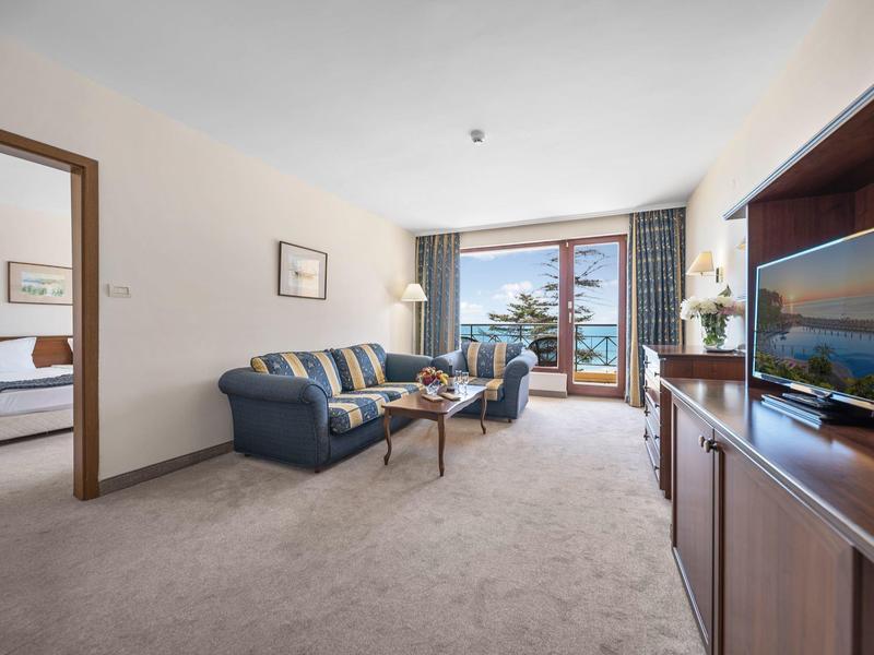 Cozy living room with sofa and armchairs, view of balcony and sea.