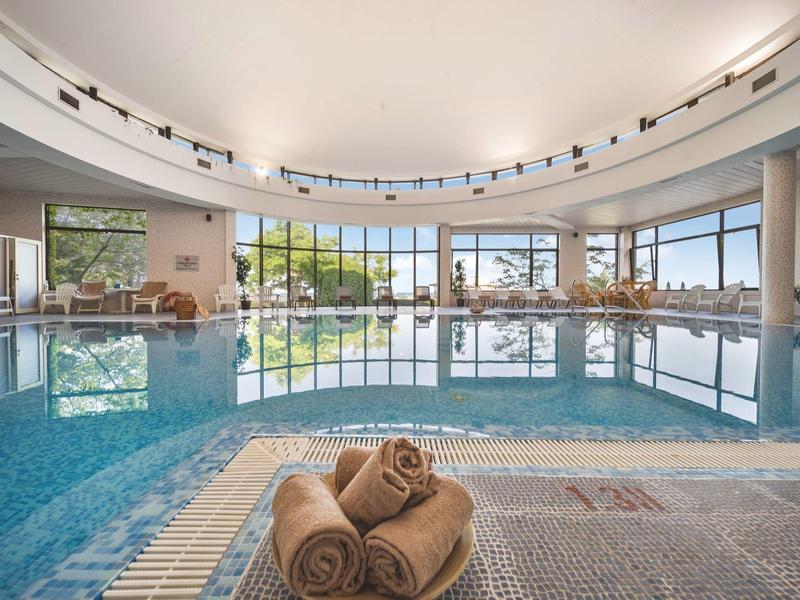 Indoor swimming pool with large windows and rolled towels in the foreground