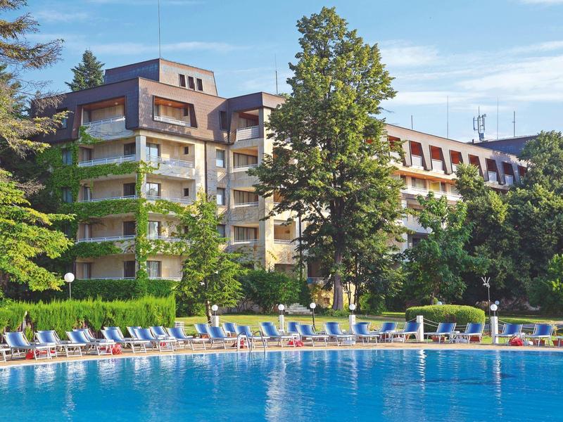 Large multi-story hotel building beside a pool with sun loungers