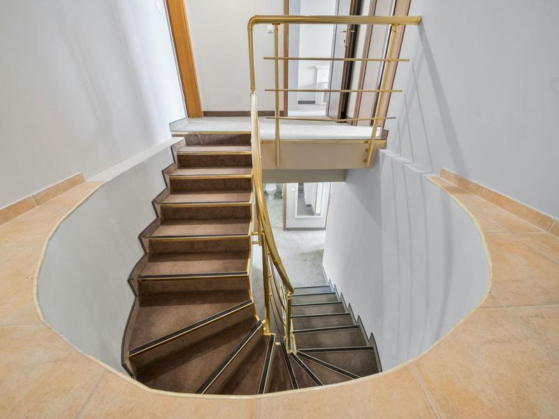 Interior staircase with a circular opening in the floor and wooden-metal railing.