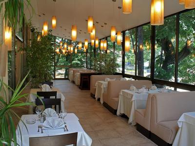 Gezellig restaurantgedeelte met grote ramen, comfortabele zitbanken en stijlvolle hanglampen.