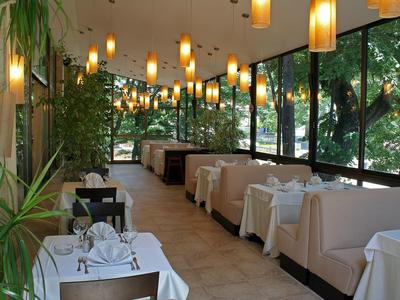 Lichte horecaruimte met grote ramen, comfortabele zitjes en witte tafelkleden.