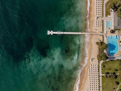 Luchtfoto van een strand, een lange pier en een zwembad naast een hotel