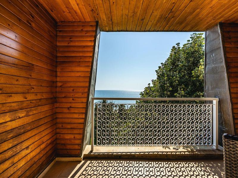 Balkon met houten bekleding en uitzicht op de zee bij helder weer.