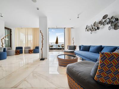 Moderní obývací pokoj s modrými pohovkami, kulatými stoly a uměním na bílé zdi.