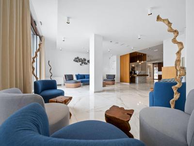 Jasný moderní obývací pokoj s modrými a šedými křesly a bílou mramorovou podlahou.