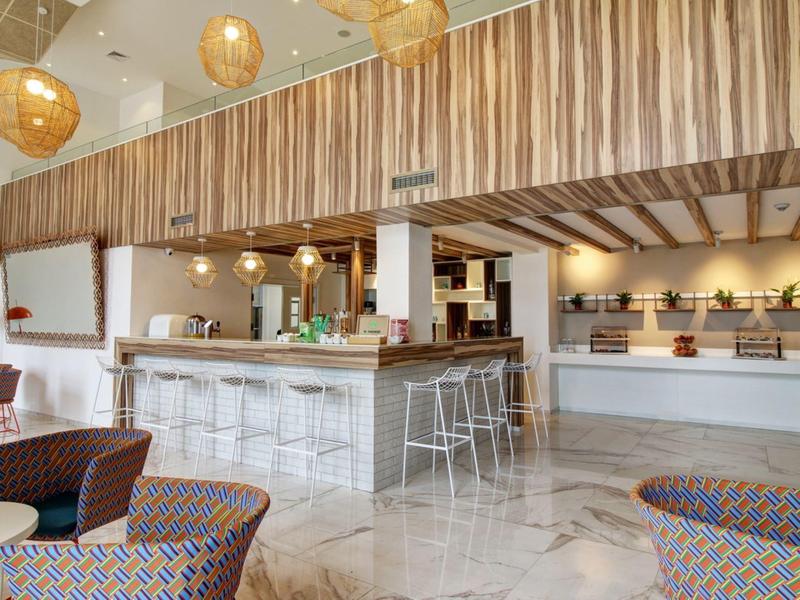Moderní hotelový interiér s barem, stoličkami a útulnou posezením.