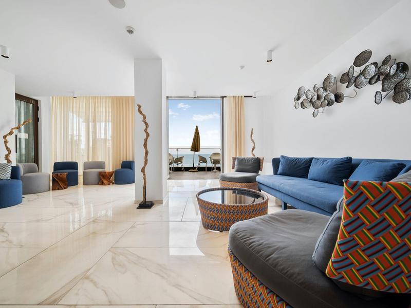 Moderní obývací pokoj s modrými pohovkami, kulatými stoly a uměním na bílé zdi.