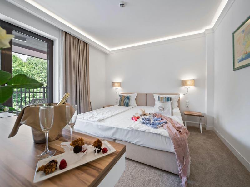 Moderní hotelový pokoj s velkou postelí, dvěma nočními stolky a dekorací na stole.