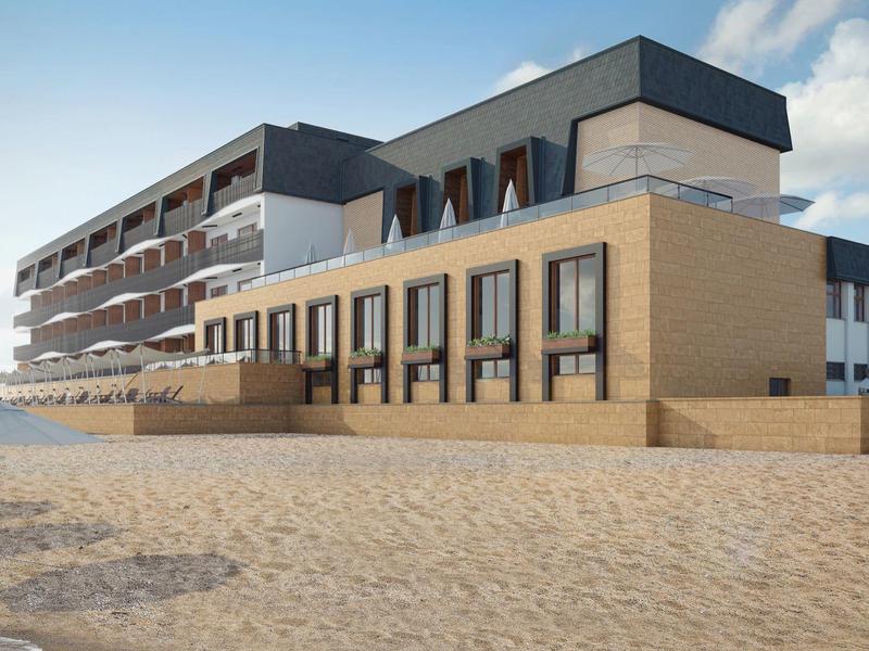 Moderní hotelová budova na pláži s pískem v popředí