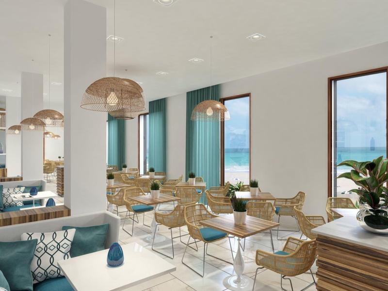 Moderní kavárna s ratanovými židlemi a modrými pohovkami u velkých oken.