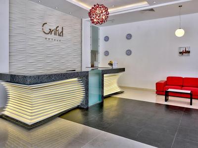 Elegant hotel reception with illuminated counter and red sofa against white wall.