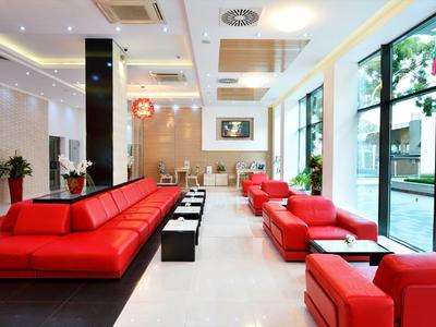 Modern hotel lobby with red sofas, glass windows, and bright floors.