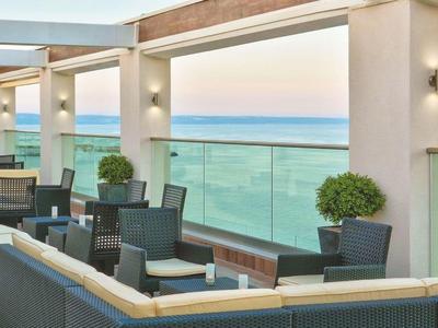 Terraza moderna con asientos y vista al mar al atardecer.