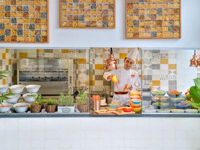 Cocina abierta con variedad de ingredientes y un cocinero trabajando en una cocina moderna de hotel.
