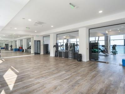 Spacious, bright gym with wooden floor and large mirrors on one wall
