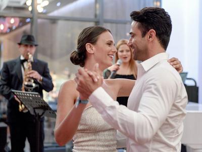 Couple dancing closely in a festive setting with live music in the background.