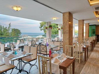 Terraza cubierta del hotel con mesas preparadas y vista al mar a la luz del día