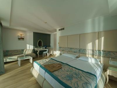 Habitación de hotel moderna con cama grande y área de estar, luminosa y soleada.