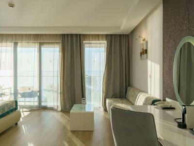 Habitación de hotel moderna con sofá, escritorio y grandes ventanas con vista a la ciudad.