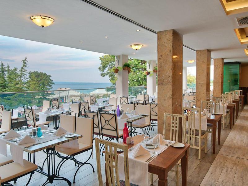 Terraza cubierta del hotel con mesas preparadas y vista al mar a la luz del día