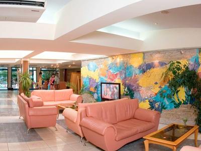 Hall d'hôtel avec canapés roses, sol clair et décoration murale colorée.