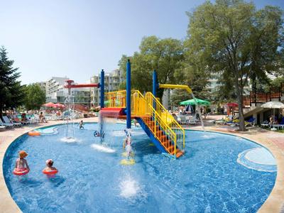 Enfants jouant dans la piscine avec aire de jeux aquatique et toboggan pendant les vacances d'été.