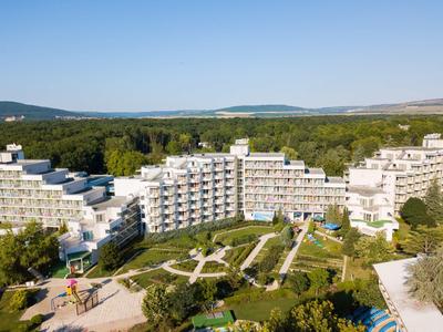 Plusieurs bâtiments d'hôtel blancs entourés de jardins verts et de sentiers sous un ciel clair.