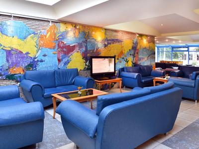 Espace lounge d'hôtel bien éclairé avec canapés bleus et art mural coloré.