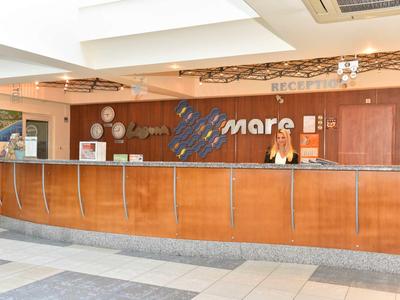 Comptoir d'accueil dans un hôtel lumineux avec boiseries et réceptionniste.