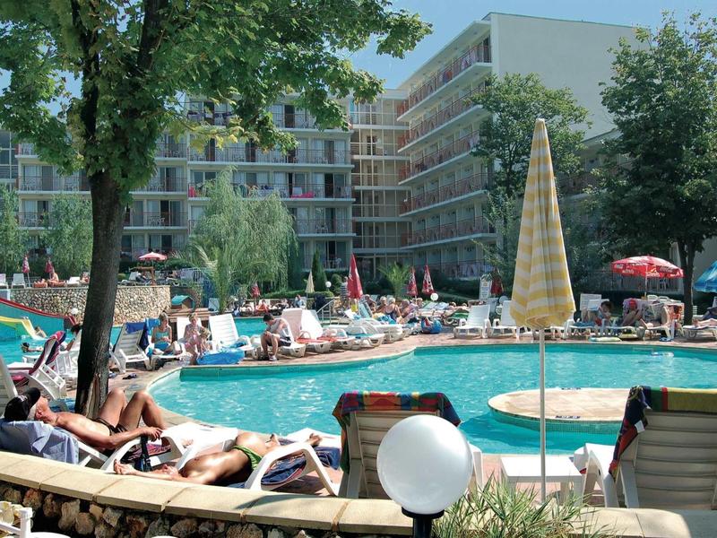 Hotel with outdoor pool and guests, surrounded by sun loungers and umbrellas