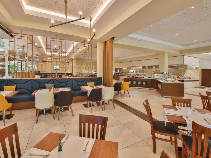 Elegant hotel restaurant with modern interior, wooden tables, and colorful chairs.