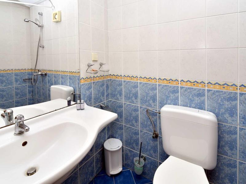 Small bathroom with white sink, toilet, and blue tiles on walls and floor.